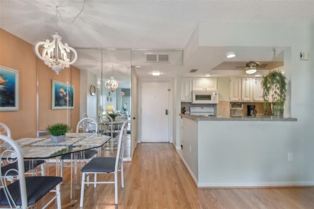 kitchen with range, light wood-type flooring, a textured ceiling, pendant lighting, and white cabinets