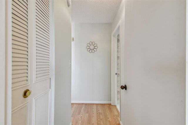 hall featuring a textured ceiling and light hardwood / wood-style flooring