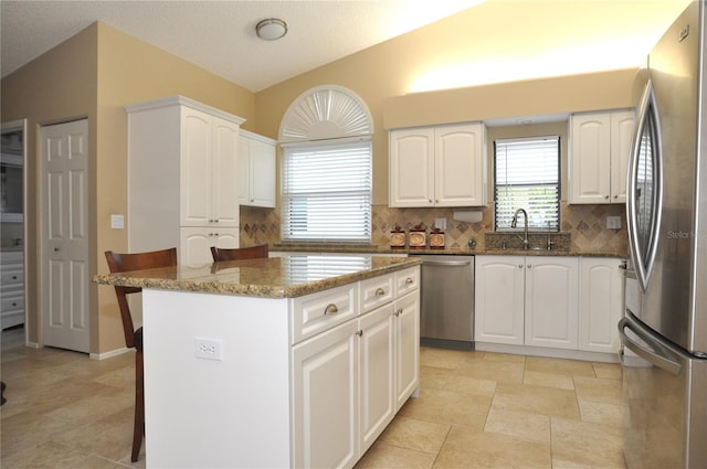 kitchen with white cabinetry, a center island, a kitchen bar, and appliances with stainless steel finishes