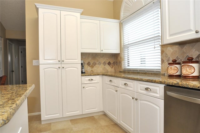 kitchen with decorative backsplash, stainless steel dishwasher, white cabinets, and dark stone countertops