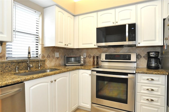 kitchen featuring dark stone countertops, white cabinetry, and appliances with stainless steel finishes