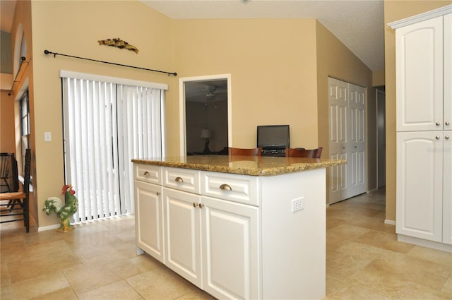 kitchen featuring white cabinets, light tile patterned floors, stone countertops, and lofted ceiling