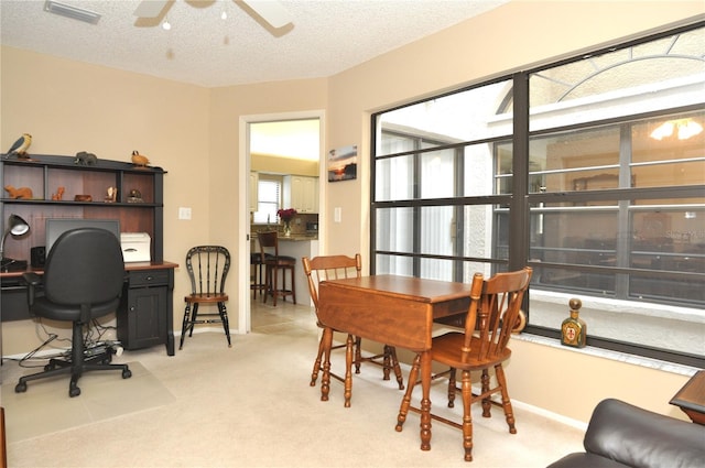 carpeted dining room featuring ceiling fan and a textured ceiling