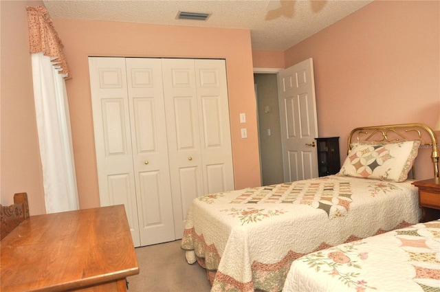 bedroom featuring a closet, ceiling fan, light colored carpet, and a textured ceiling