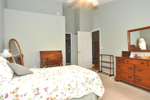 carpeted bedroom featuring ceiling fan and a high ceiling