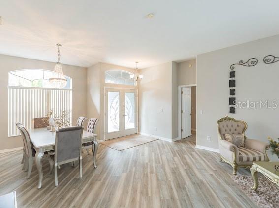 dining area with french doors, a chandelier, and light wood-type flooring