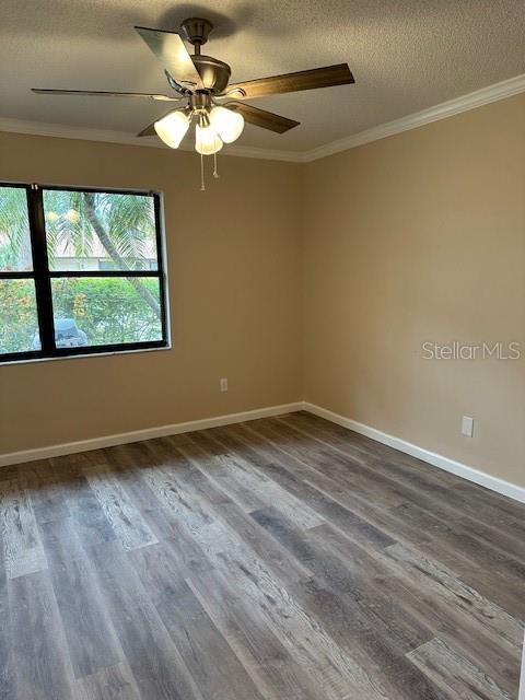 spare room with a textured ceiling, ceiling fan, ornamental molding, and wood-type flooring