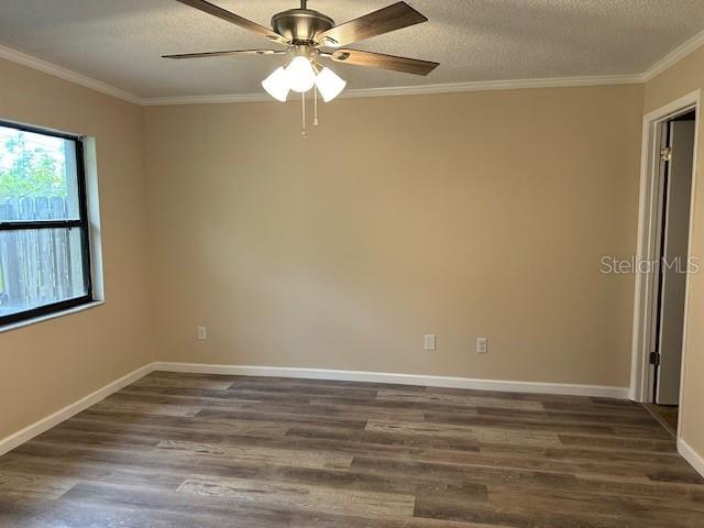 spare room with a textured ceiling, ceiling fan, crown molding, and dark hardwood / wood-style flooring