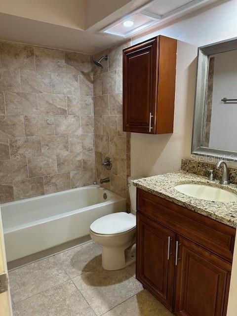 full bathroom with toilet, tiled shower / bath, tile patterned floors, and vanity