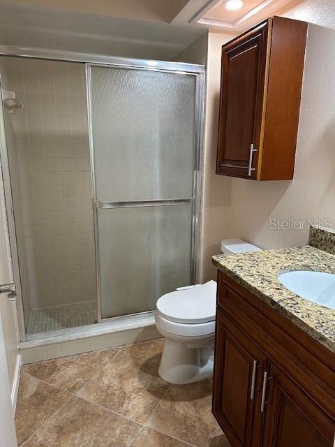 bathroom with toilet, vanity, and walk in shower