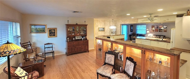 bar with ceiling fan and light wood-type flooring