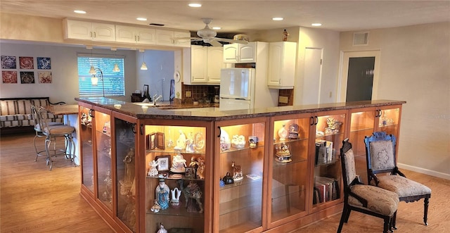 bar with white cabinetry, white refrigerator, light hardwood / wood-style floors, decorative backsplash, and ceiling fan