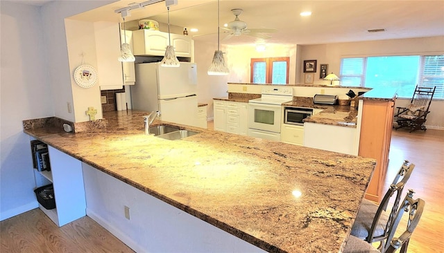 kitchen featuring white cabinetry, kitchen peninsula, white appliances, hanging light fixtures, and sink