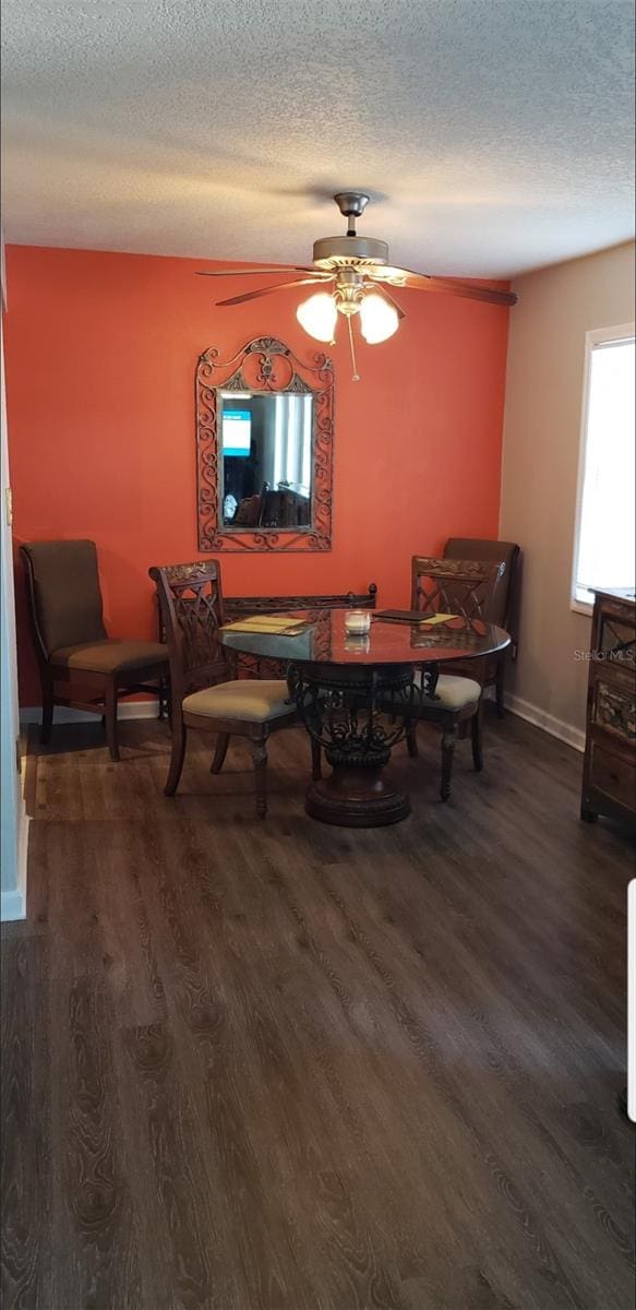 dining room with dark wood-type flooring, a textured ceiling, and ceiling fan