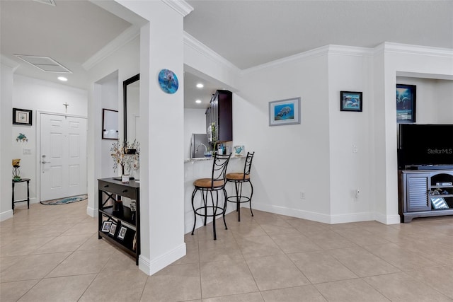 kitchen with a breakfast bar, stainless steel fridge, light tile patterned floors, and ornamental molding