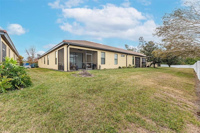 rear view of house featuring a yard and a sunroom