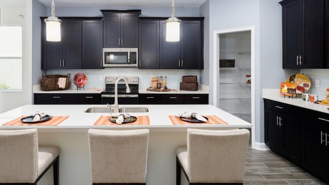 kitchen with appliances with stainless steel finishes, pendant lighting, a kitchen bar, and sink