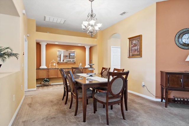 carpeted dining space with ornate columns and an inviting chandelier