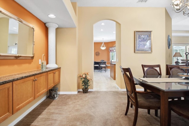 carpeted dining room with decorative columns