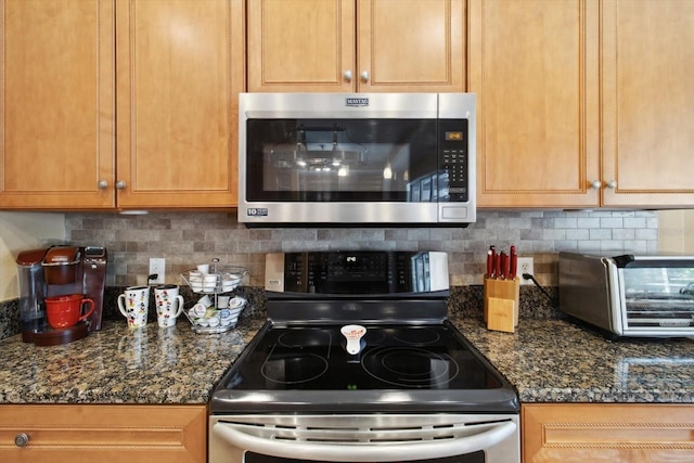 kitchen featuring dark stone counters, stainless steel appliances, and tasteful backsplash