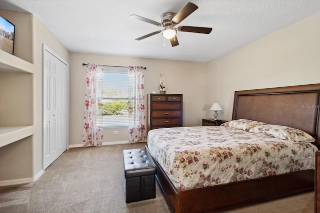 bedroom with ceiling fan, a closet, light carpet, and a textured ceiling