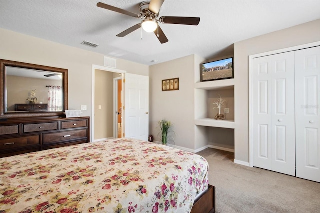 bedroom featuring a closet, a textured ceiling, ceiling fan, and light carpet