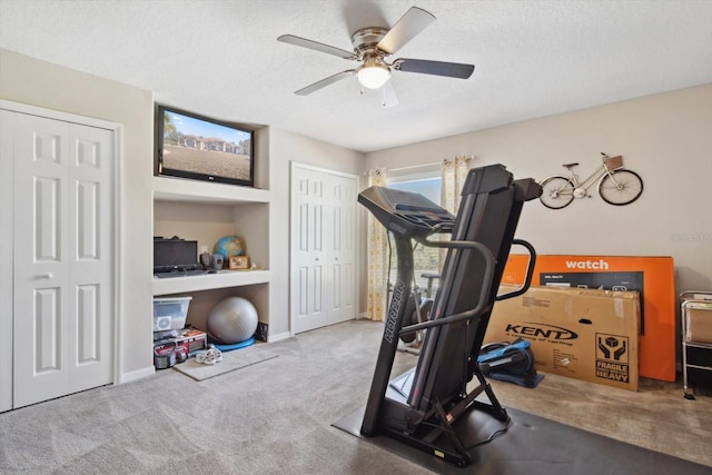 exercise room featuring built in shelves, a textured ceiling, ceiling fan, and carpet