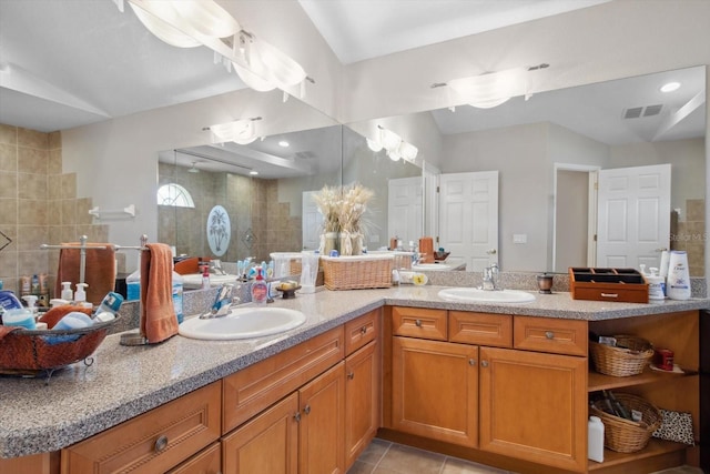 bathroom featuring tile patterned flooring, vaulted ceiling, a tile shower, and vanity