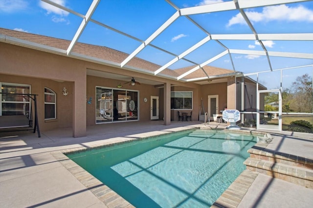 view of pool with a patio area, ceiling fan, and glass enclosure