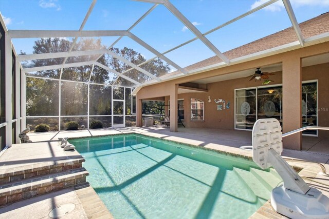 view of swimming pool with ceiling fan, glass enclosure, and a patio