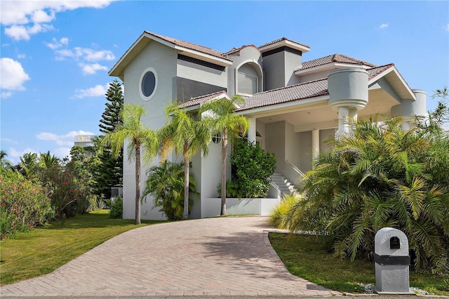 mediterranean / spanish-style house with a balcony and a front lawn