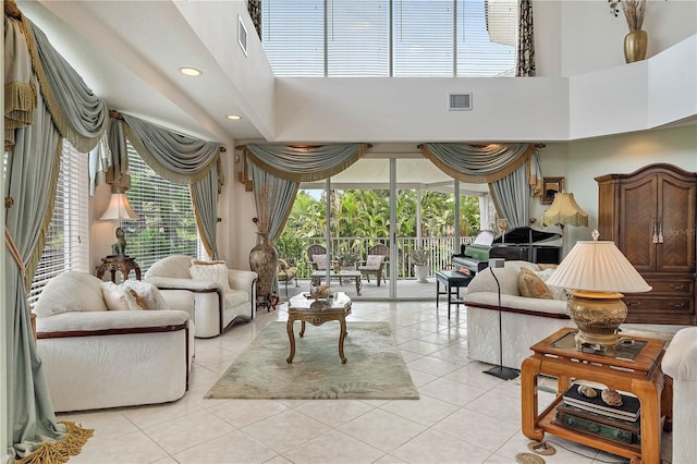 living room featuring a wealth of natural light, a towering ceiling, and light tile patterned flooring