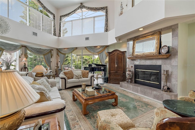 living room featuring a tiled fireplace and a high ceiling