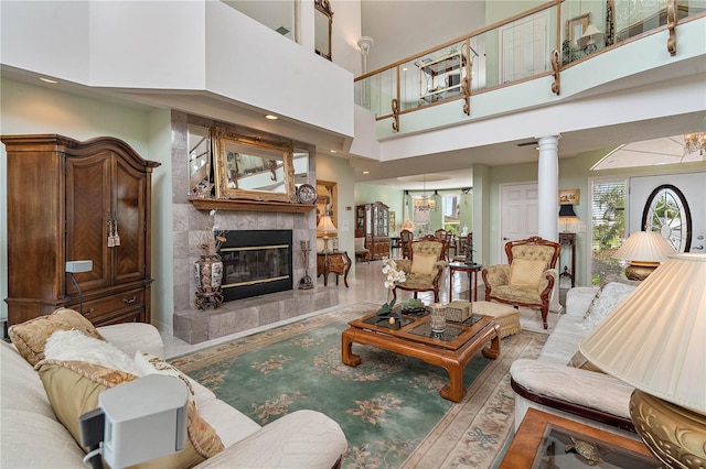 living room with decorative columns, a towering ceiling, and a fireplace