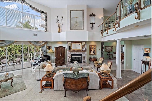 living room featuring a tile fireplace, decorative columns, a high ceiling, and a wealth of natural light