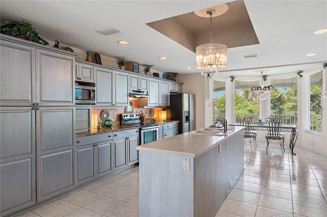 kitchen featuring appliances with stainless steel finishes, gray cabinetry, and a raised ceiling