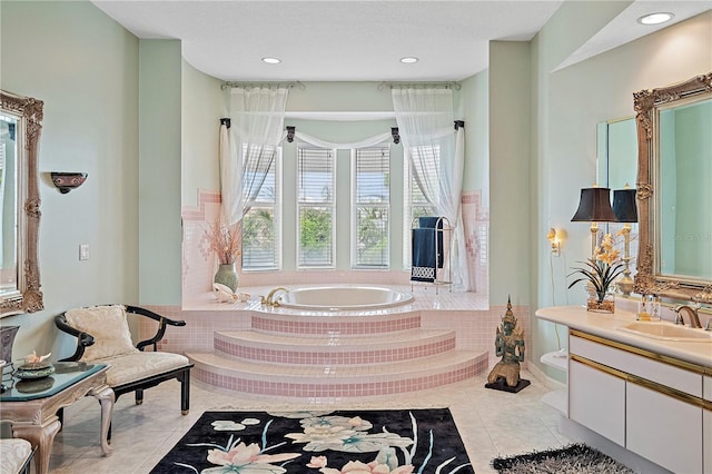 bathroom featuring tile patterned flooring, tiled tub, and vanity