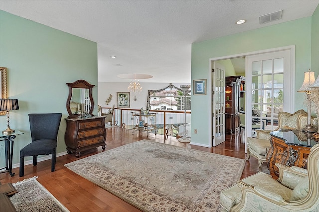 living area with a notable chandelier, dark wood-type flooring, and a textured ceiling