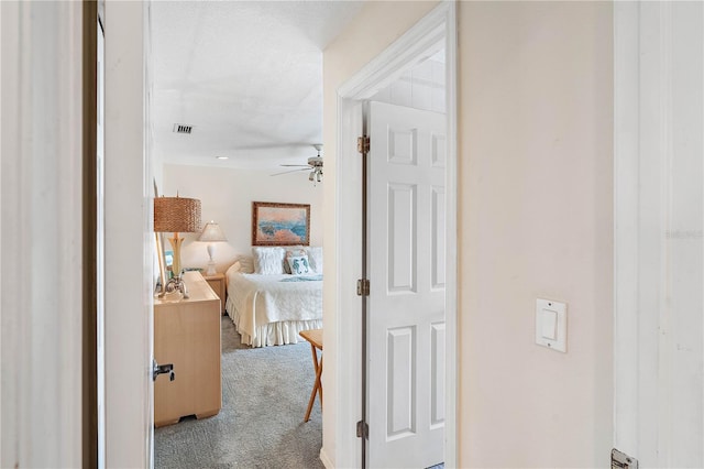 hallway featuring light carpet and a textured ceiling