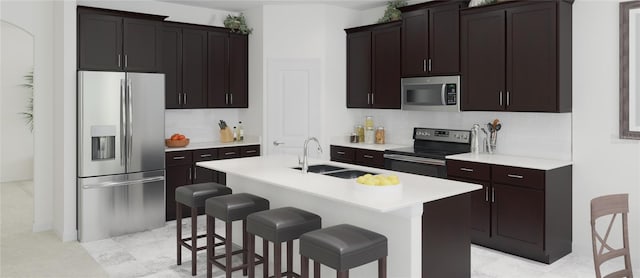 kitchen featuring an island with sink, appliances with stainless steel finishes, a breakfast bar, and sink