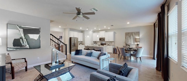 living room featuring sink, ceiling fan, and light hardwood / wood-style flooring