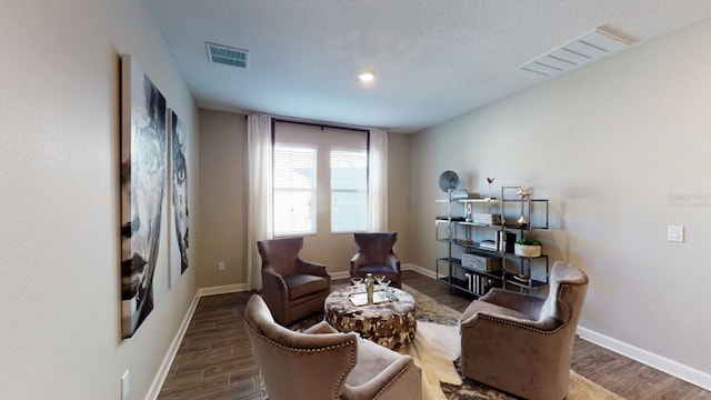 sitting room with a textured ceiling and dark wood-type flooring