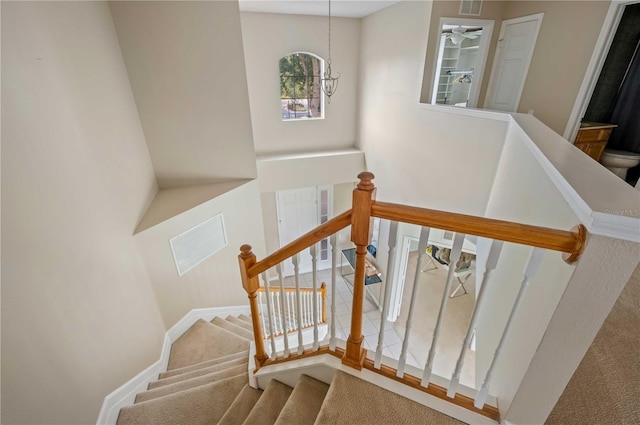 stairs with carpet flooring and a notable chandelier