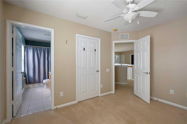 unfurnished bedroom with light carpet, connected bathroom, and ceiling fan