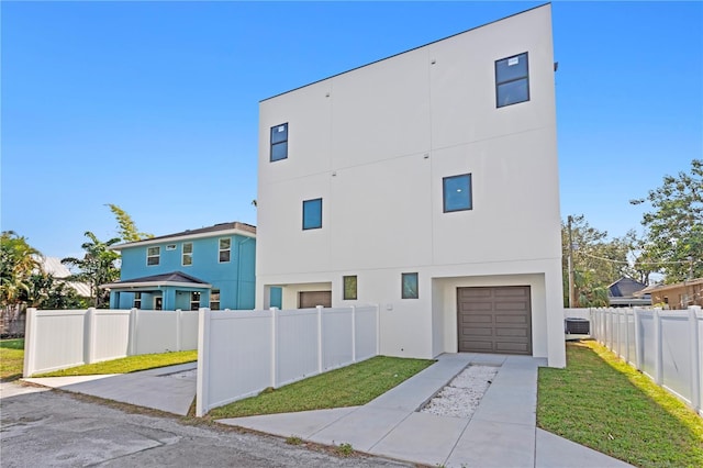 exterior space with cooling unit, a front lawn, and a garage