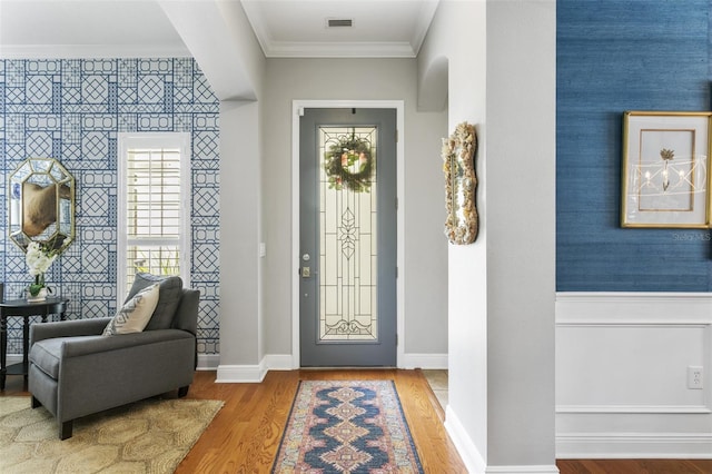 foyer entrance with wood-type flooring and crown molding