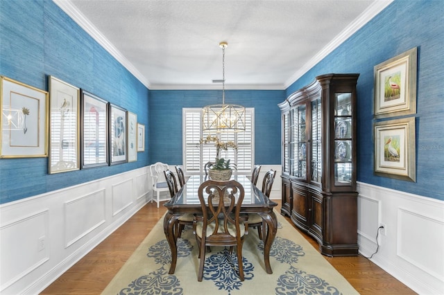 dining area with wood-type flooring, a notable chandelier, and ornamental molding