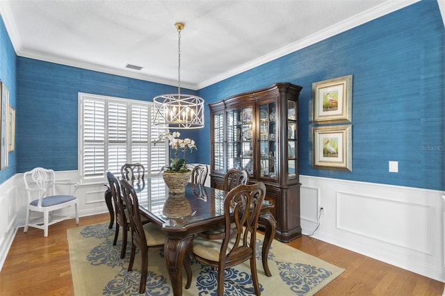 dining area featuring an inviting chandelier, crown molding, and hardwood / wood-style flooring