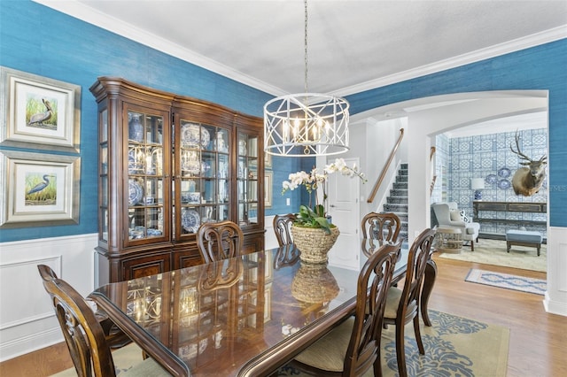 dining room with wood-type flooring, crown molding, and an inviting chandelier