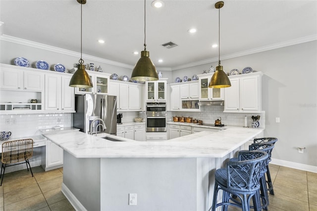 kitchen featuring light stone countertops, white cabinets, stainless steel appliances, sink, and hanging light fixtures